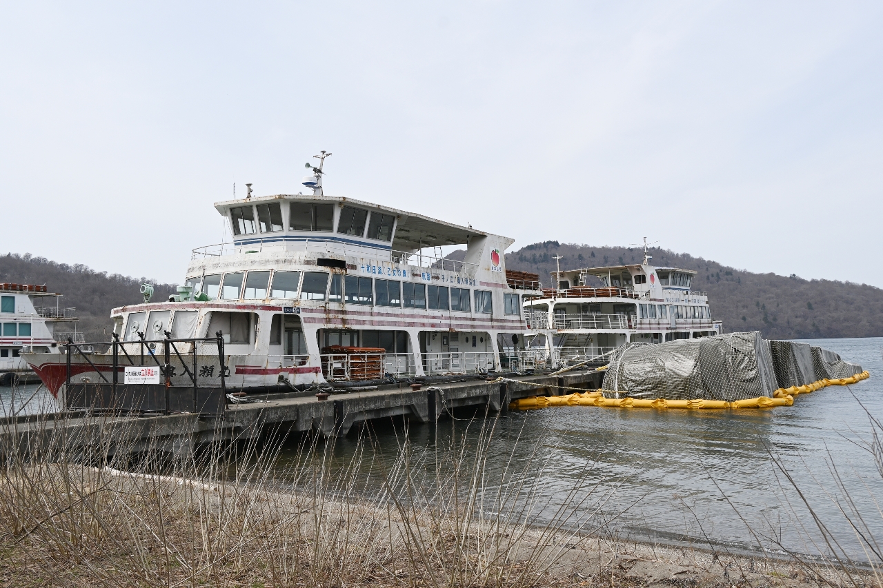 十和田湖畔宇樽部地区の桟橋に放置されている遊覧船。うち1隻は横転したままとなっている=4月、十和田市