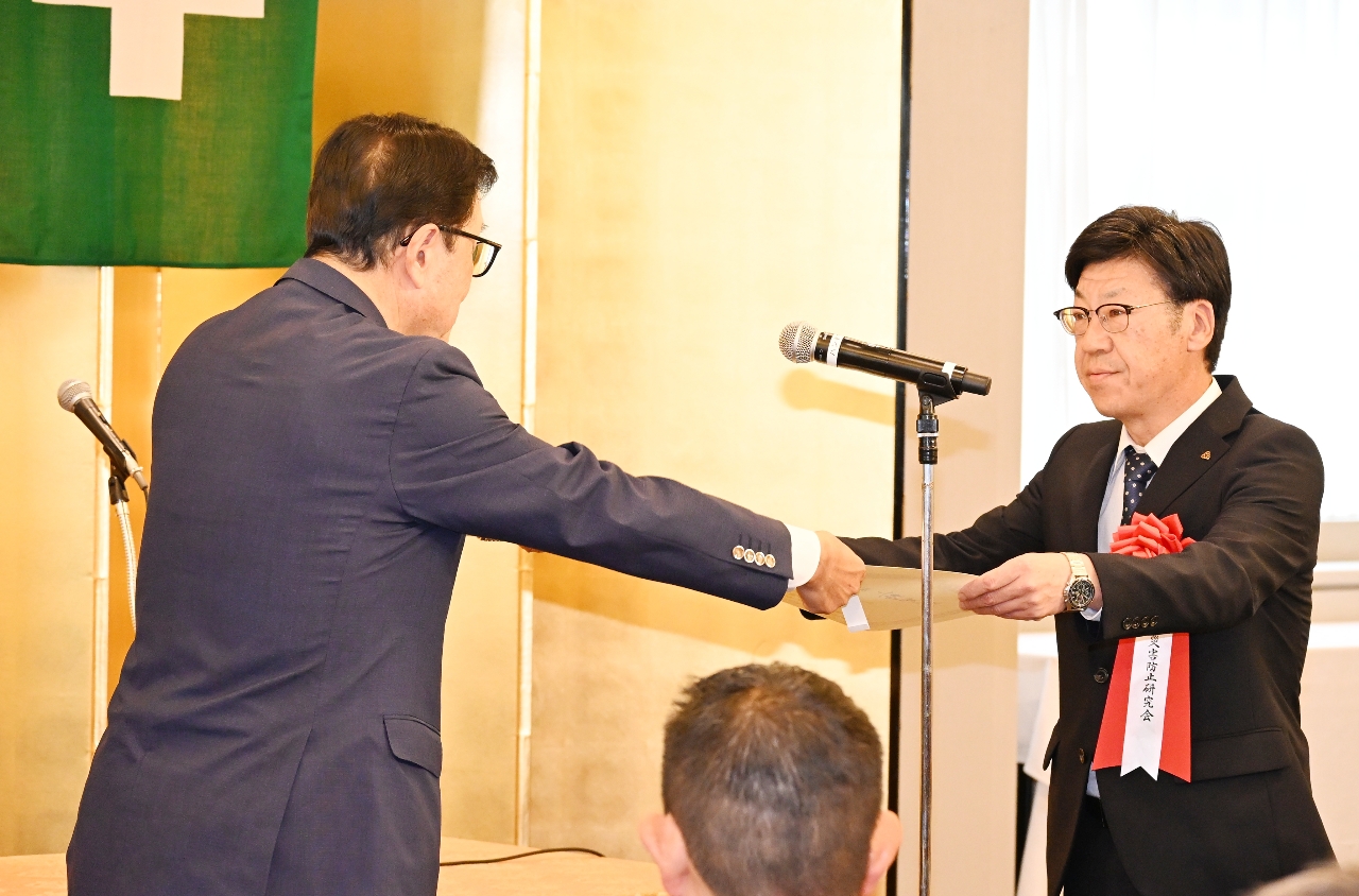 表彰状を受け取る八戸災害防止研究会の種市健吉さん（右）＝１日、東京都内