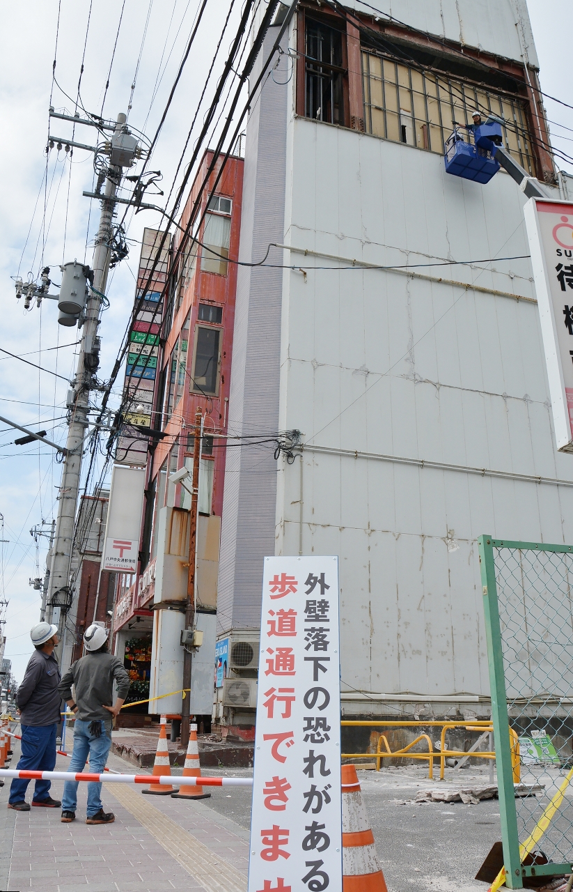 地震の影響で崩れた外壁の修繕が始まったポストコアビル=3日、八戸市長横町