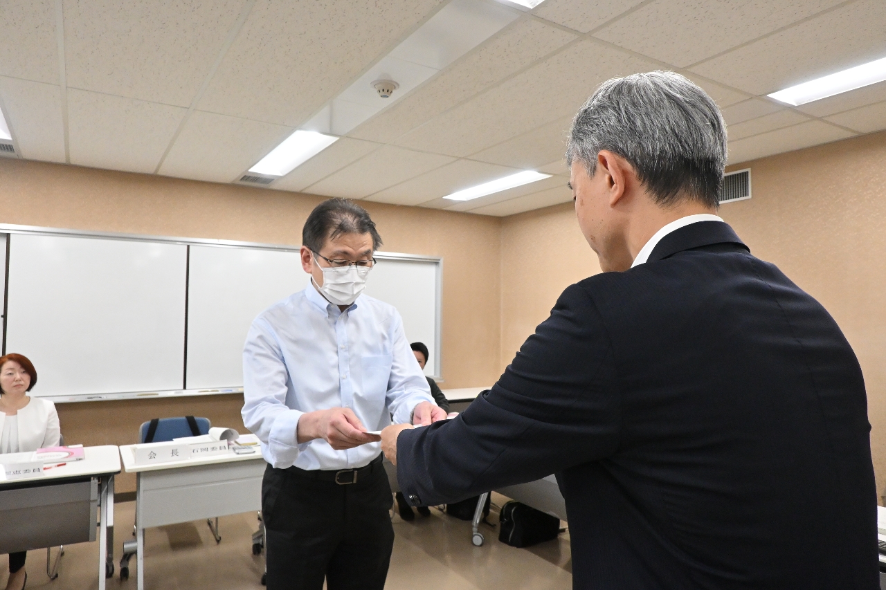 石岡隆司会長(左)に諮問書を渡す角井伸一局長=3日、青森市