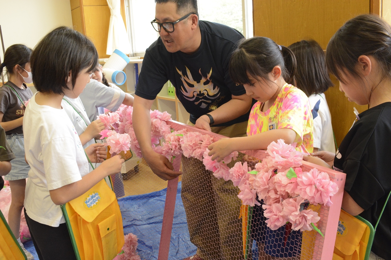 吹上山車組のメンバーから教わりながら山車飾りの制作を体験する児童=6月、八戸市立吹上小