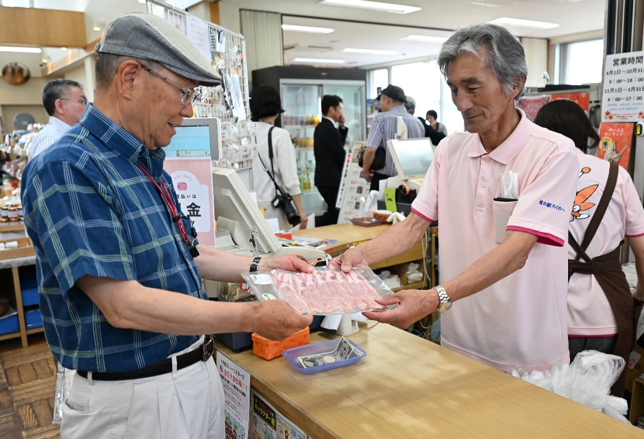 8年ぶりに青森県内での販売が復活したおいらせハーブポークを買い求める買い物客(左)=9日、六戸町