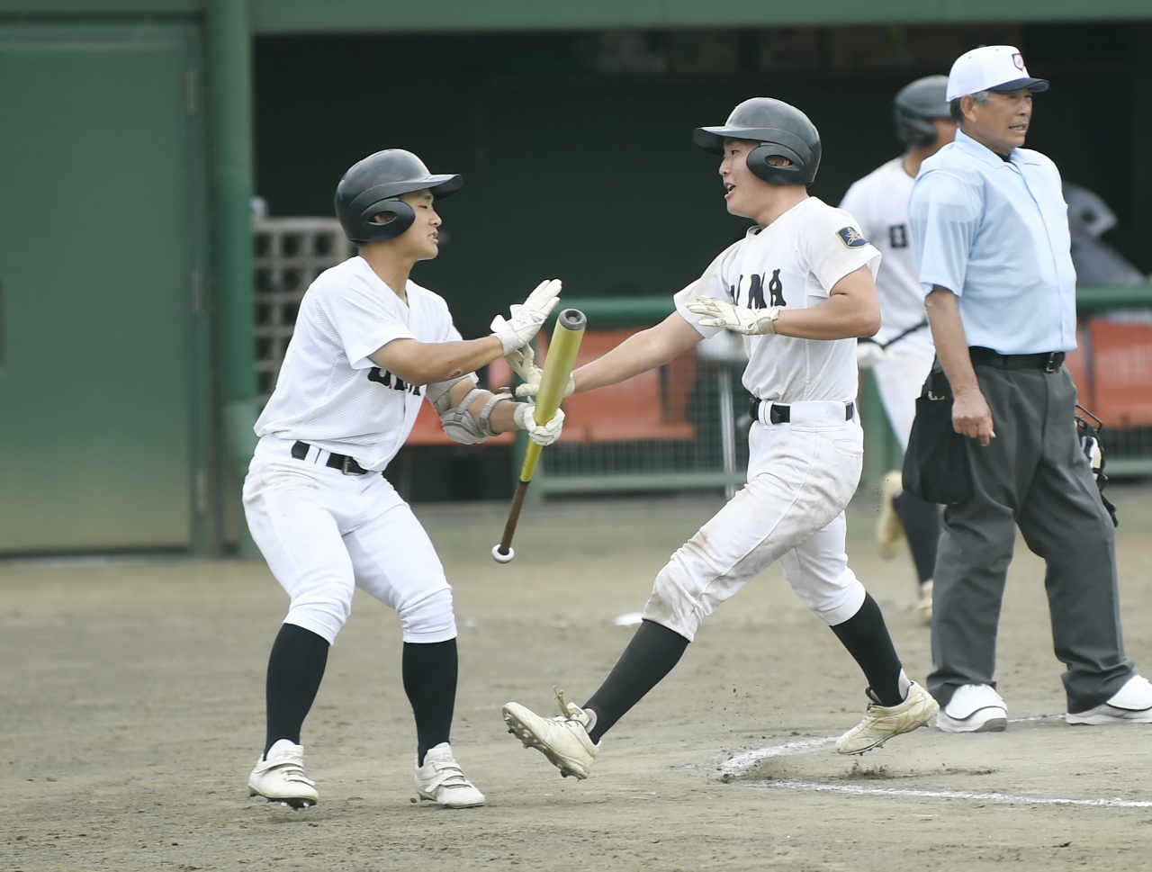 【1回戦・大間―五農】6回、適時打で生還し仲間に迎えられる大間の山本柊登(左から2人目)=六戸メイプル