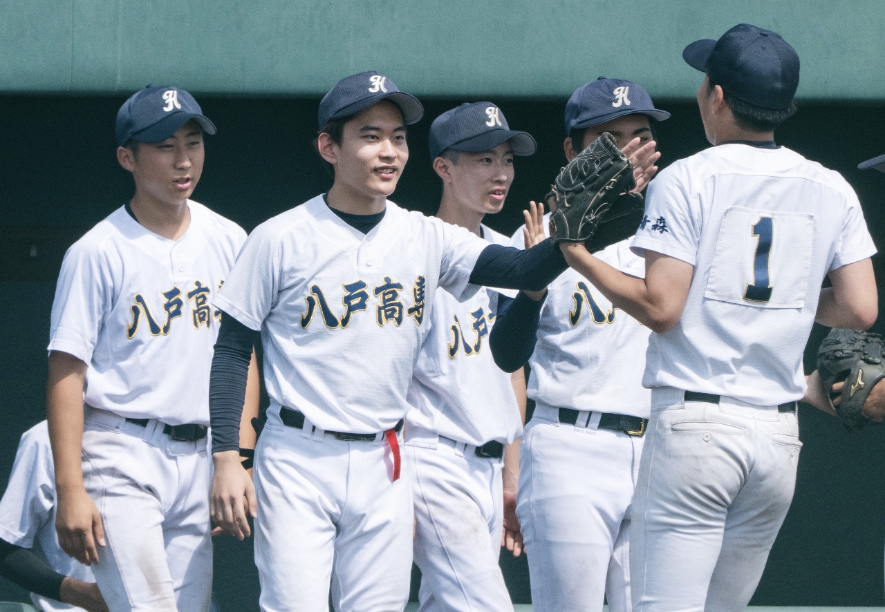 2回まで無失点に抑えた八高専ナインを笑顔で迎える川村昂史朗監督(左から2人目)=八戸東球場