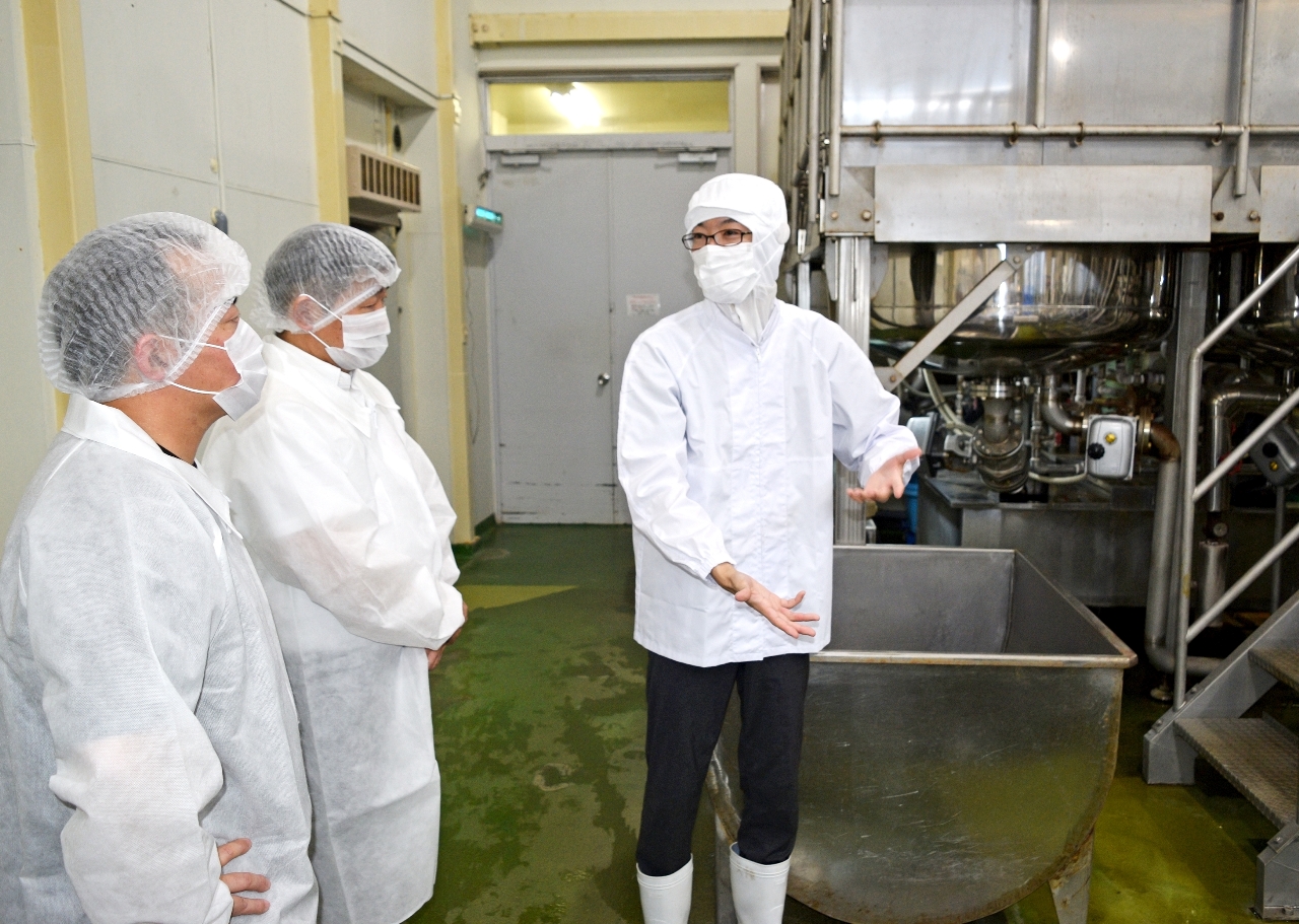 かねご製餡の担当者(右)から製造工程の説明を受けるバイヤーら=15日、八戸市