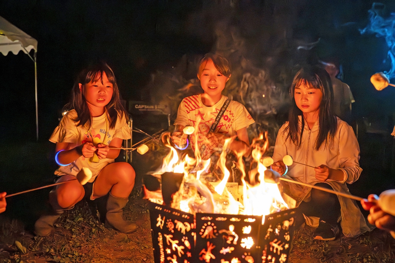 たき火でマシュマロを焼く子どもたち
