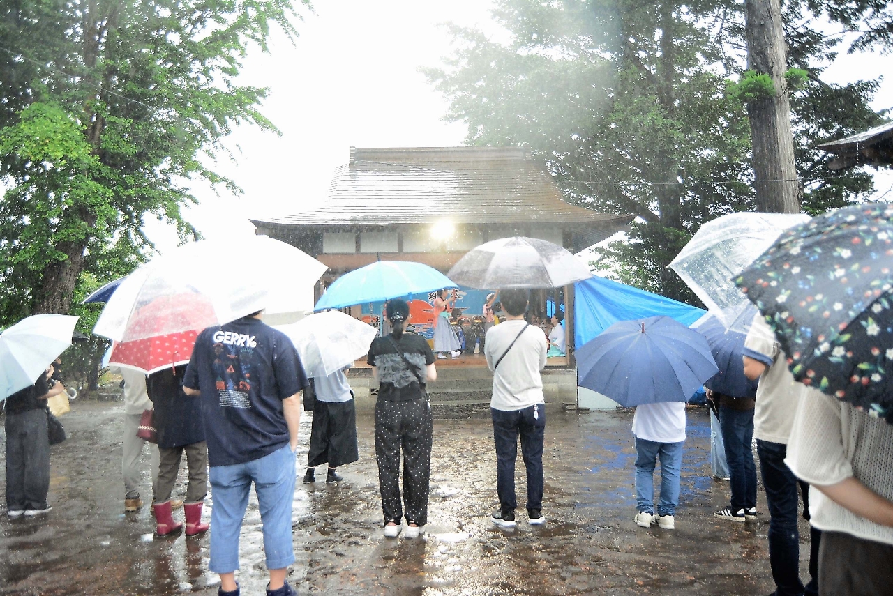 雨傘を差す多くの地域住民が舞台を見守った