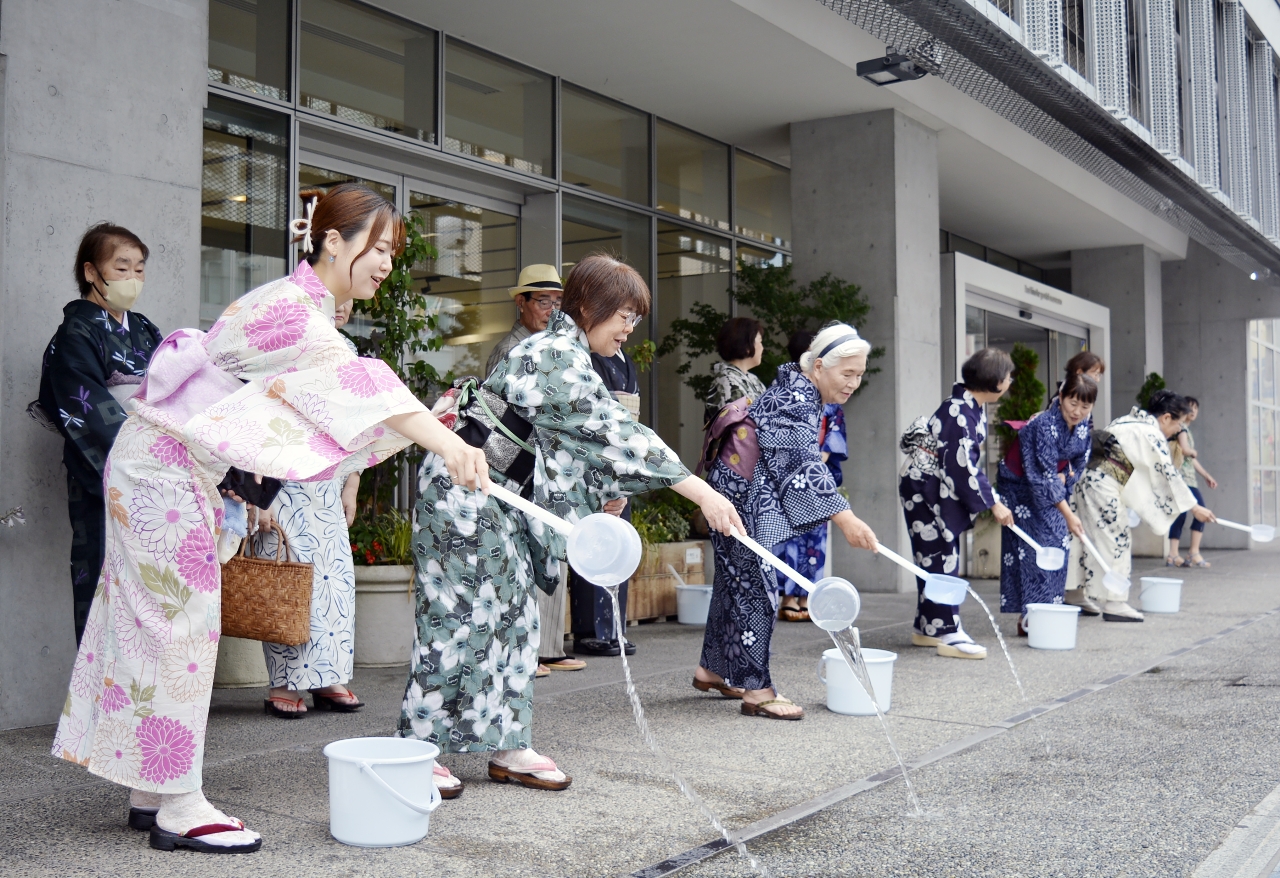 ひしゃくで打ち水をする参加者