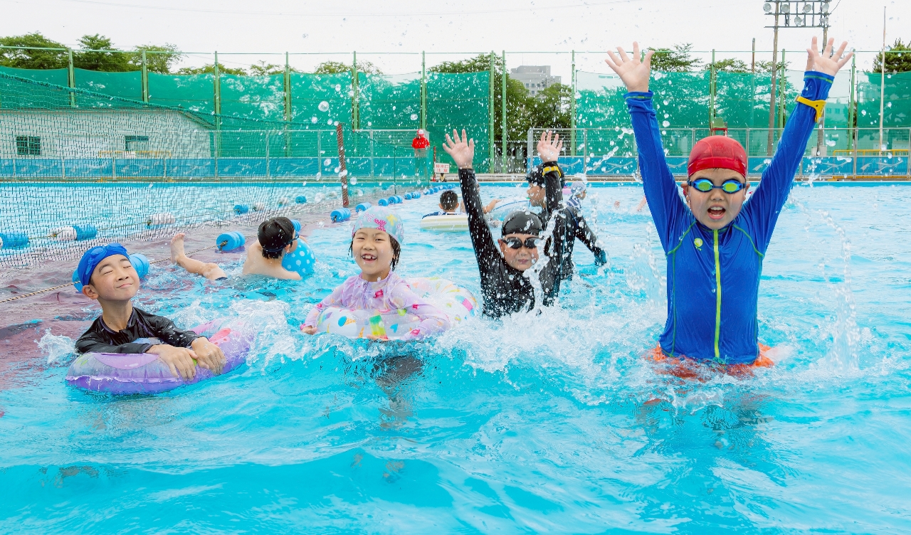 水しぶきを上げてはしゃぐ子どもたち=18日、八戸市長根公園の市民プール(大粒来仁撮影)