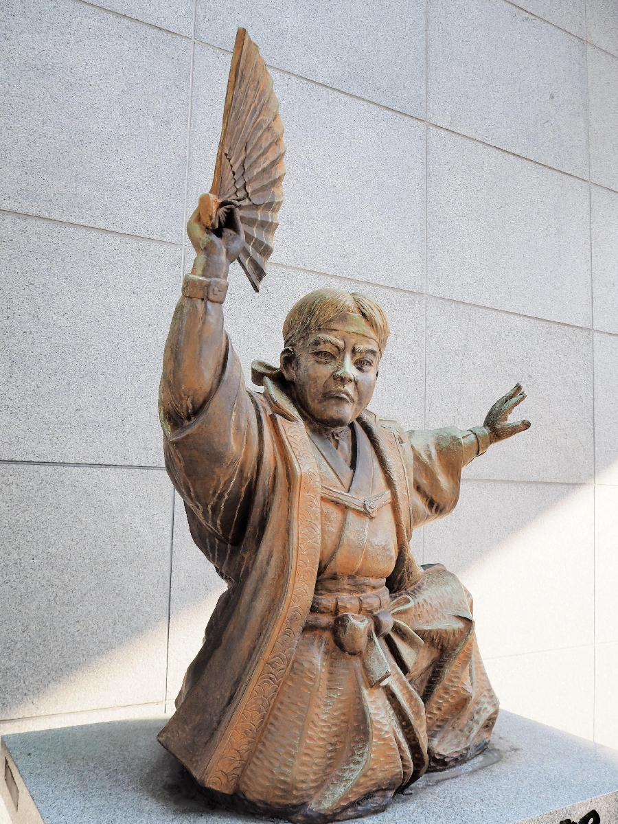 陣羽織を着て「オッペケペー節」を歌う川上音二郎の像=福岡市博多区