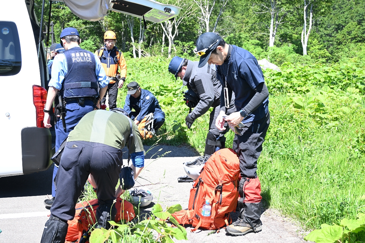 遭難者を探すため、入山前に装備を確認する捜索隊員=6月29日、青森市