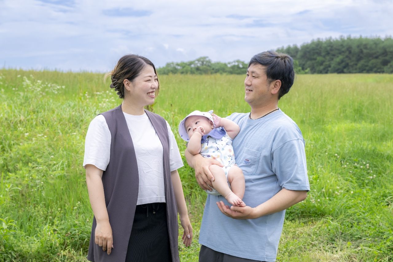故郷で社長業と育児を両立する佐々木陸衣さん(左)。長男海周くんを抱く夫の拓也さんを穏やかな表情で見つめる=7月下旬、洋野町