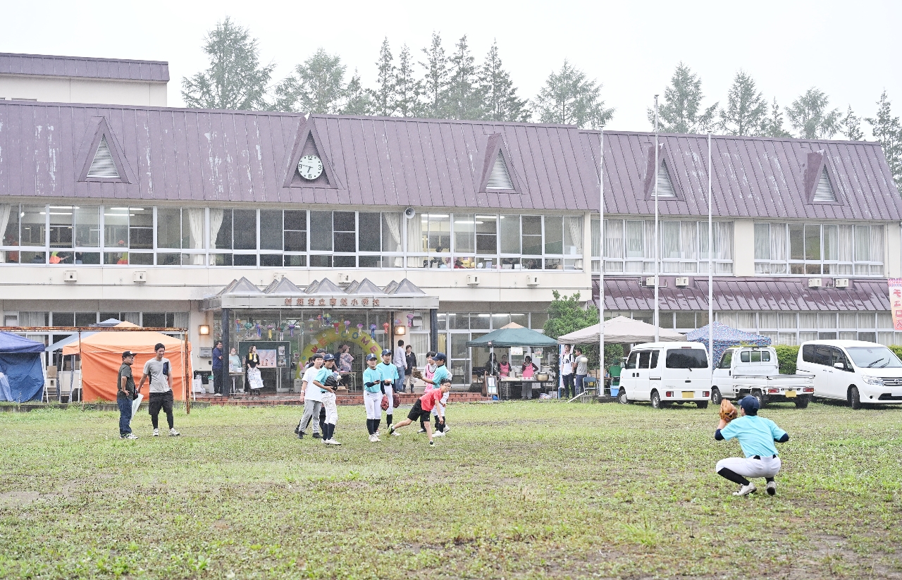 閉校となった旧西越小校舎前で遊ぶ子どもたち=25日、新郷村