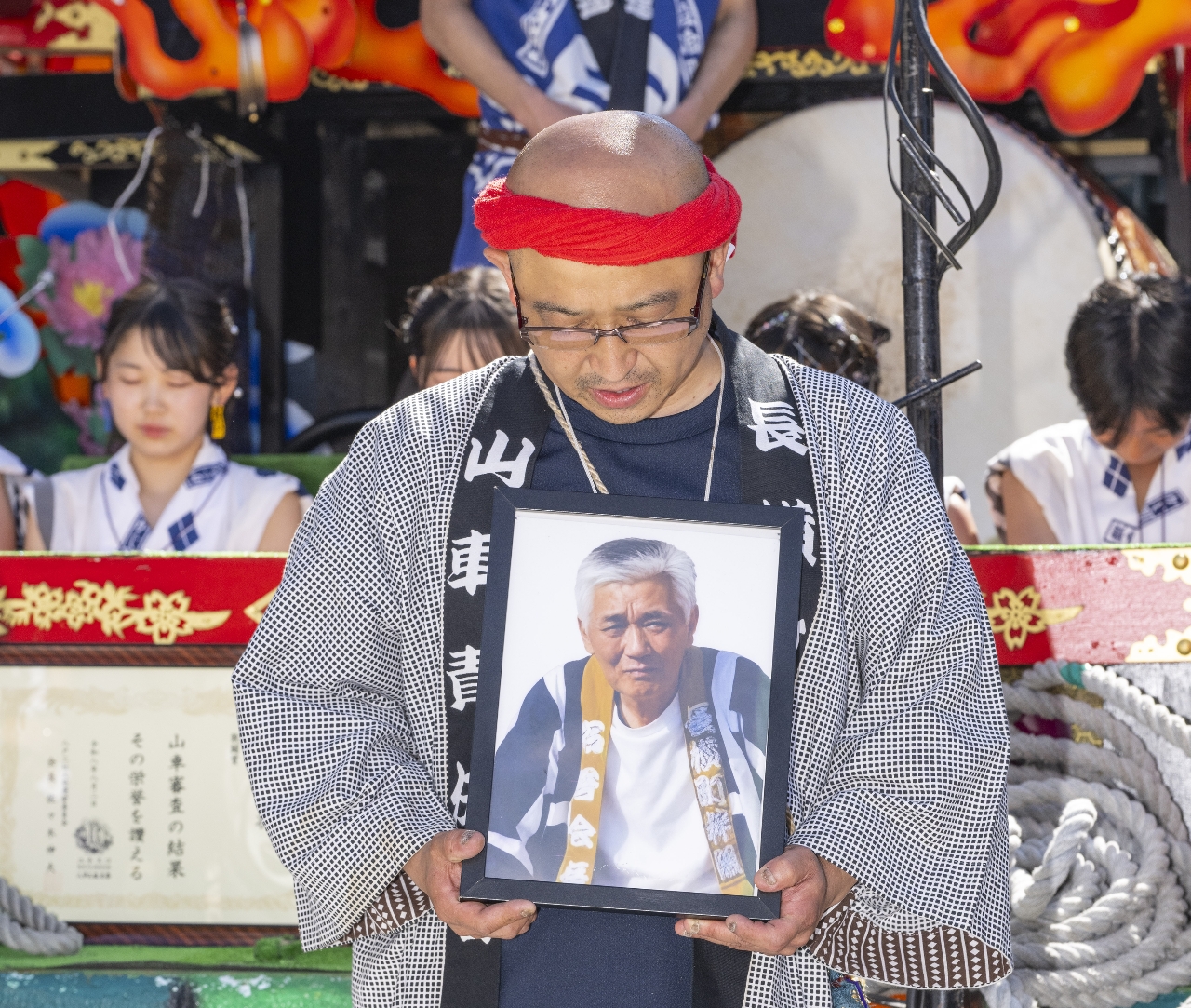 「九車別れ」で十日市雅一さんの遺影を手に黙とうする菅原鉄也さん=3日
