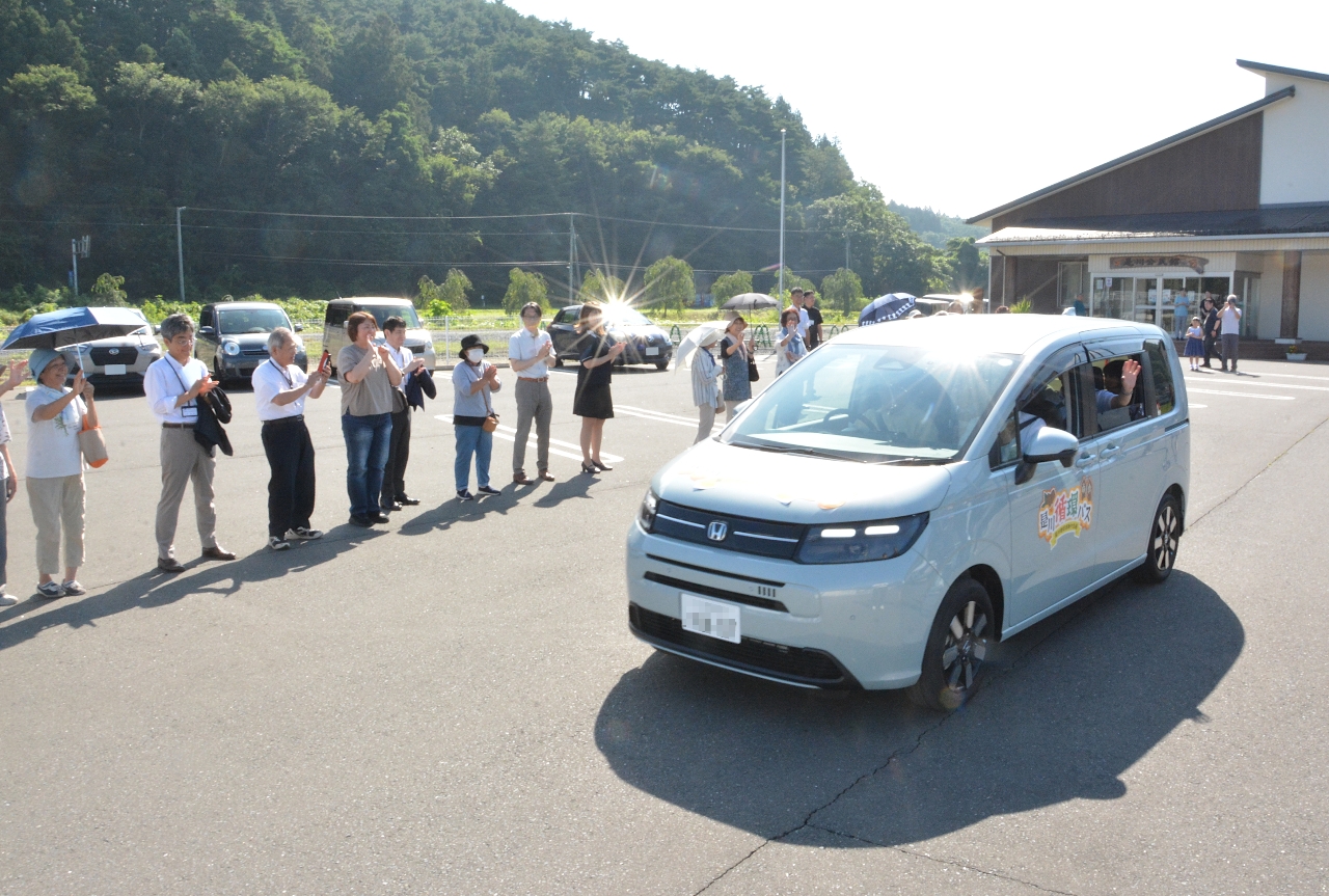 住民に見送られて出発する循環バス第１便の車両＝５日、八戸市立是川公民館