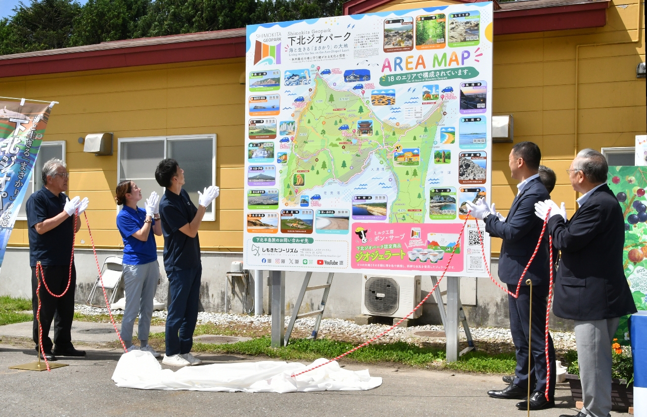 下北ジオパークをPRする看板の完成を祝う関係者=5日、むつ市田名部のミルク工房ボン・サーブ