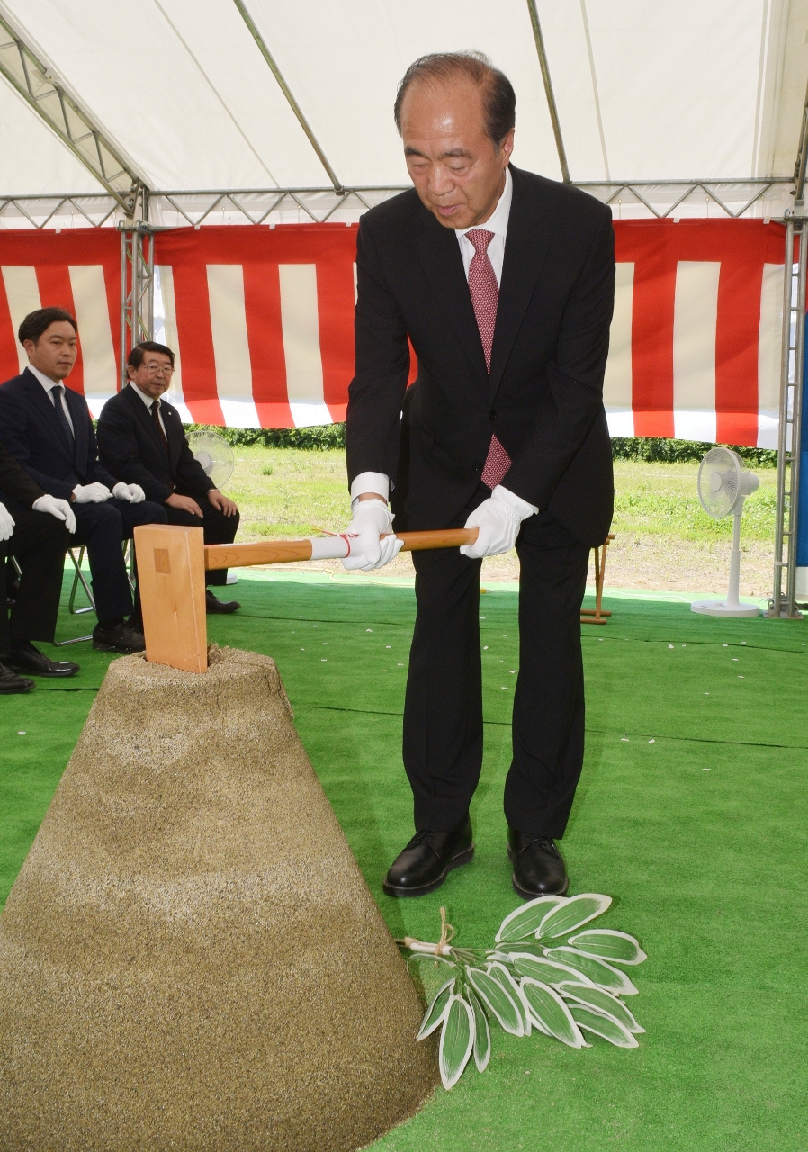 くわ入れを行う駒井庄三郎社長=6日、八戸市