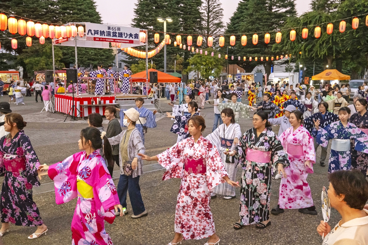 大きな輪を作り盆踊りを楽しむ参加者＝７日、八戸市庁前市民広場