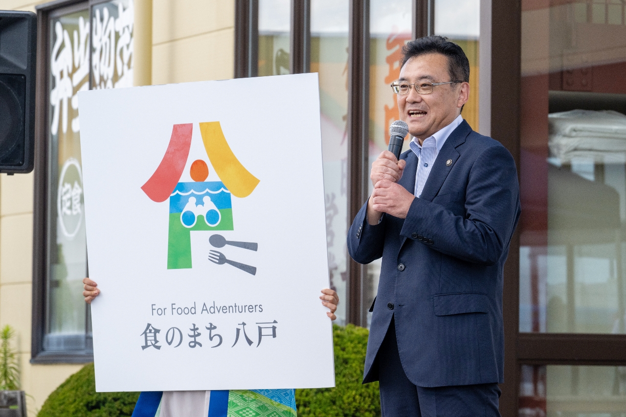 「八戸」と「食」の漢字をモチーフとしたロゴマーク。双眼鏡のデザインが「食の冒険者」を連想させる＝８日、八戸市