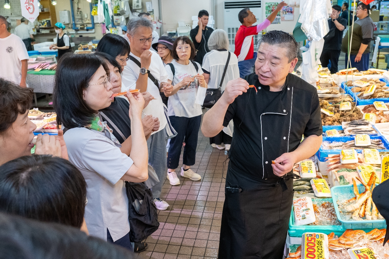 城前孝史さん（右）から食材の選び方について学ぶ参加者＝８日、八戸市