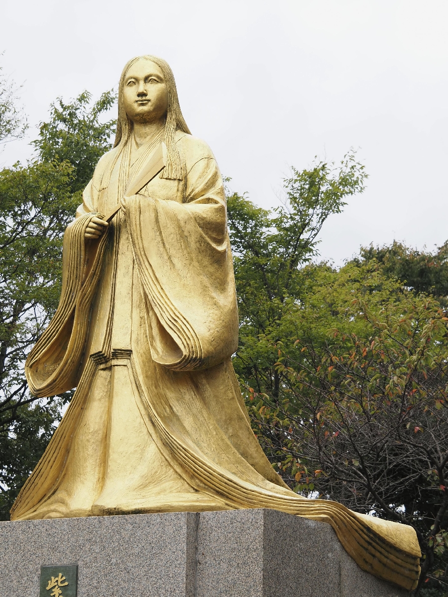 　十二単を着ておうぎを持つ金色の紫式部の銅像＝福井県越前市