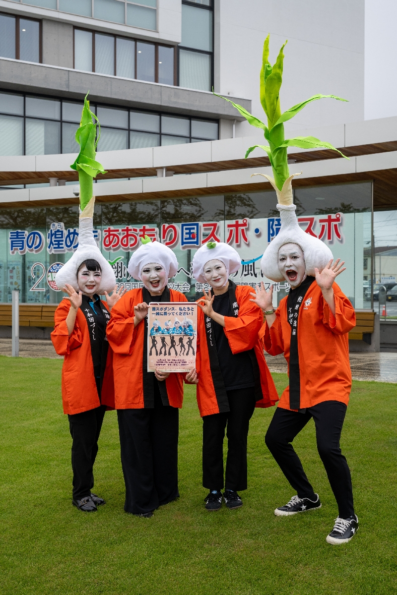 白塗りの顔に、十和田市特産のニンニクのかぶり物を付けた市職員による４人組キャラクター「十和田にんにく娘」＝１２日、十和田市役所