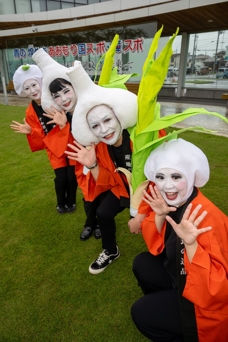白塗りの顔に、十和田市特産のニンニクのかぶり物を付けた市職員による4人組キャラクター「十和田にんにく娘」=12日、十和田市役所