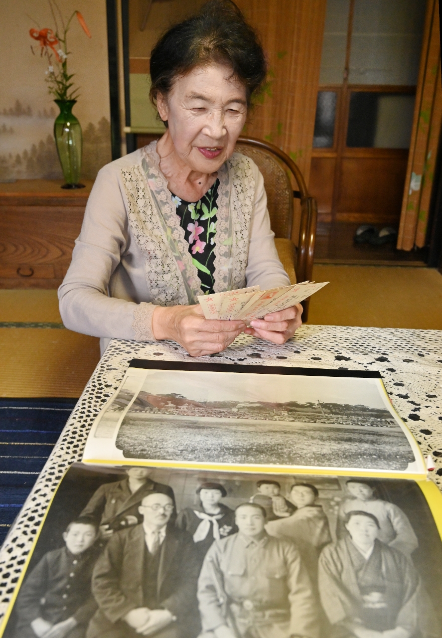 父が戦地から母に送ったはがきを眺める田中恭子さん。父やペリリュー島関係の写真も大きく引き伸ばしてファイルに収めている=10日、六戸町