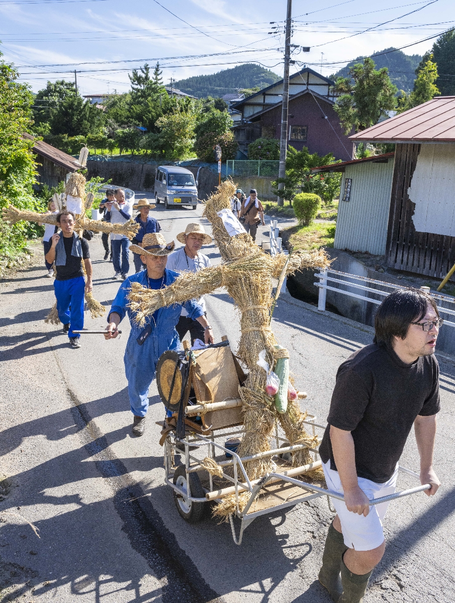 男女一対のわら人形を連れて練り歩き、五穀豊穣や家内安全を願う虫送り行事＝１６日、南部町