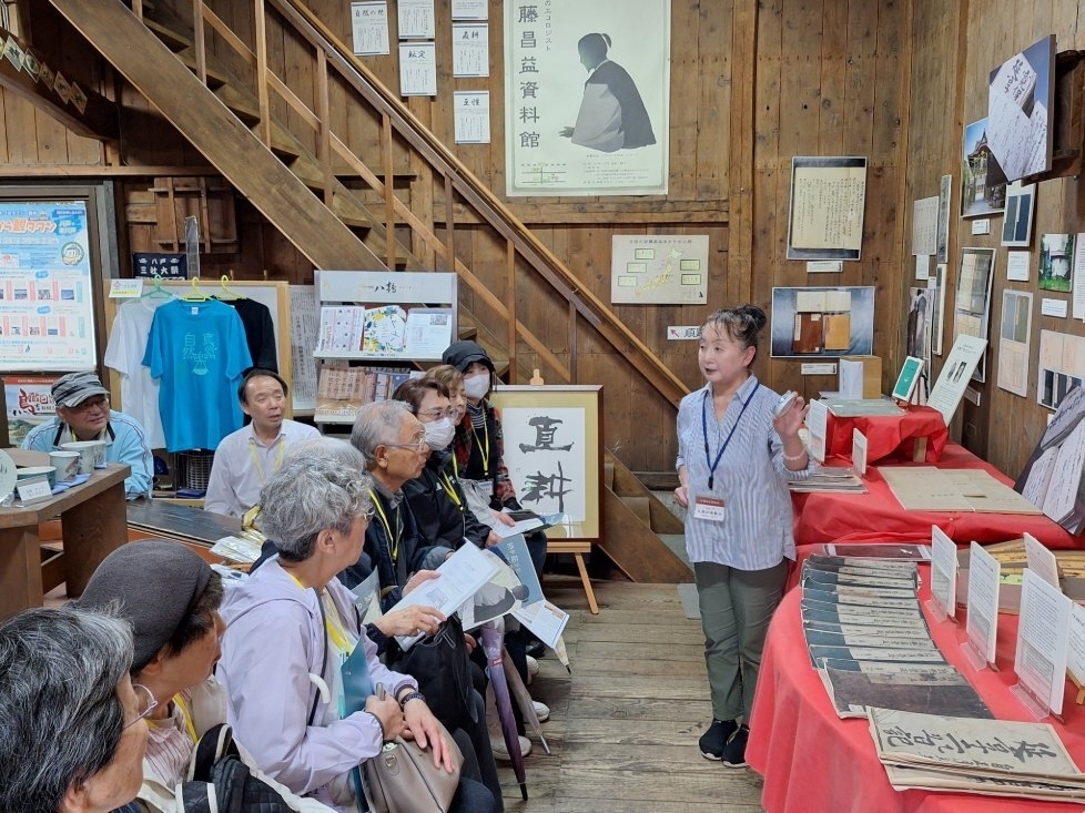 安藤昌益資料館で入館者に説明をしている久保沢陸奥子さん(同館提供)
