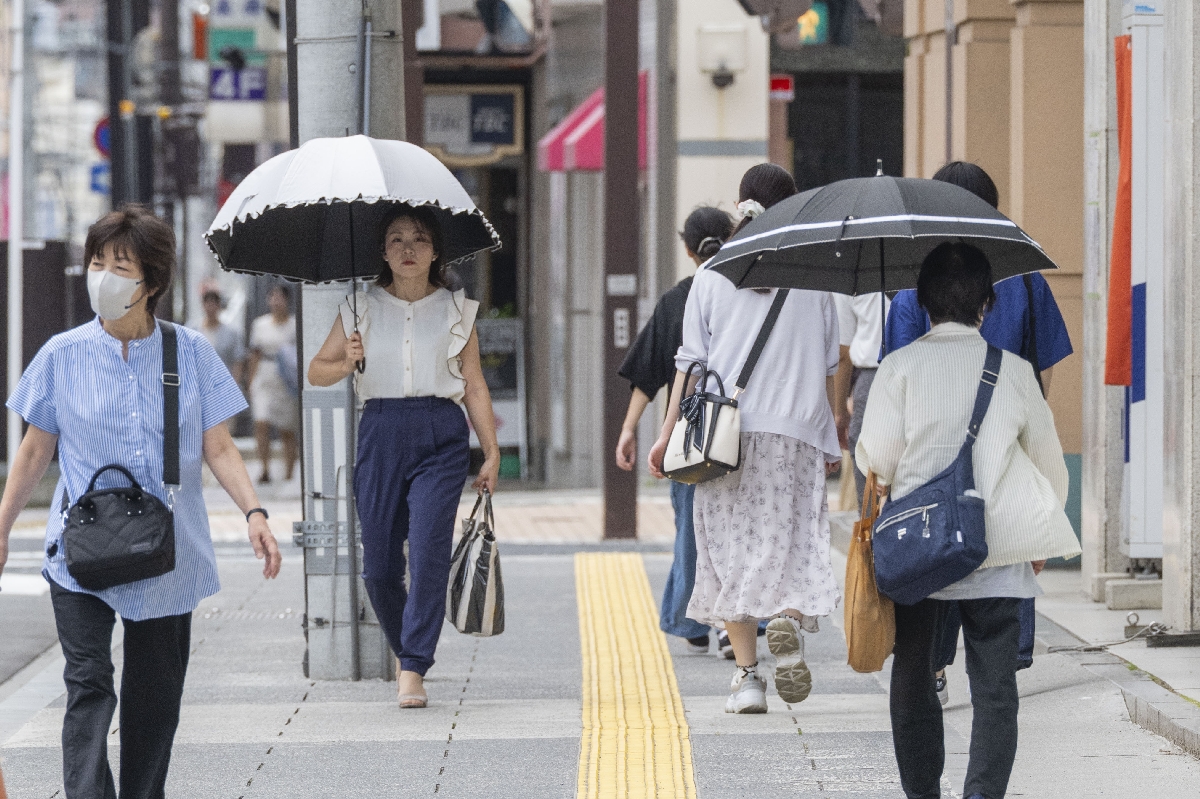 日傘を差したり、涼しげな服装で歩く市民＝１８日、八戸市中心街