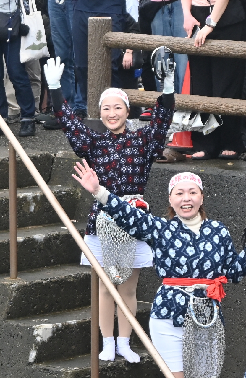 素潜り実演前に手を挙げて見物客にアピールする萱場和さん(左)=2日、久慈市