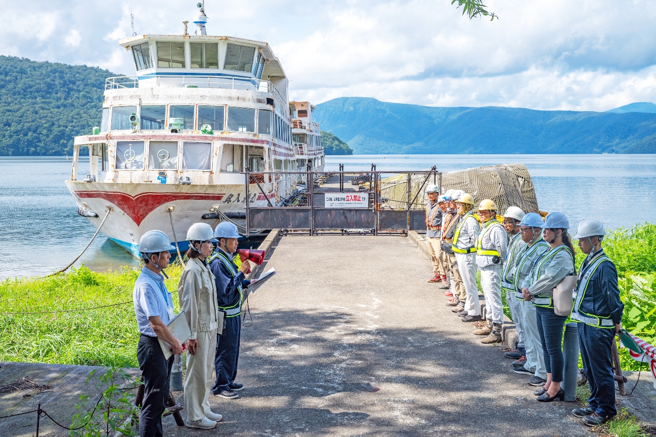 放置された遊覧船の行政代執行開始を宣言する青森県上北県土整備事務所の澤里秀典所長(左から3人目)=26日、十和田湖畔宇樽部