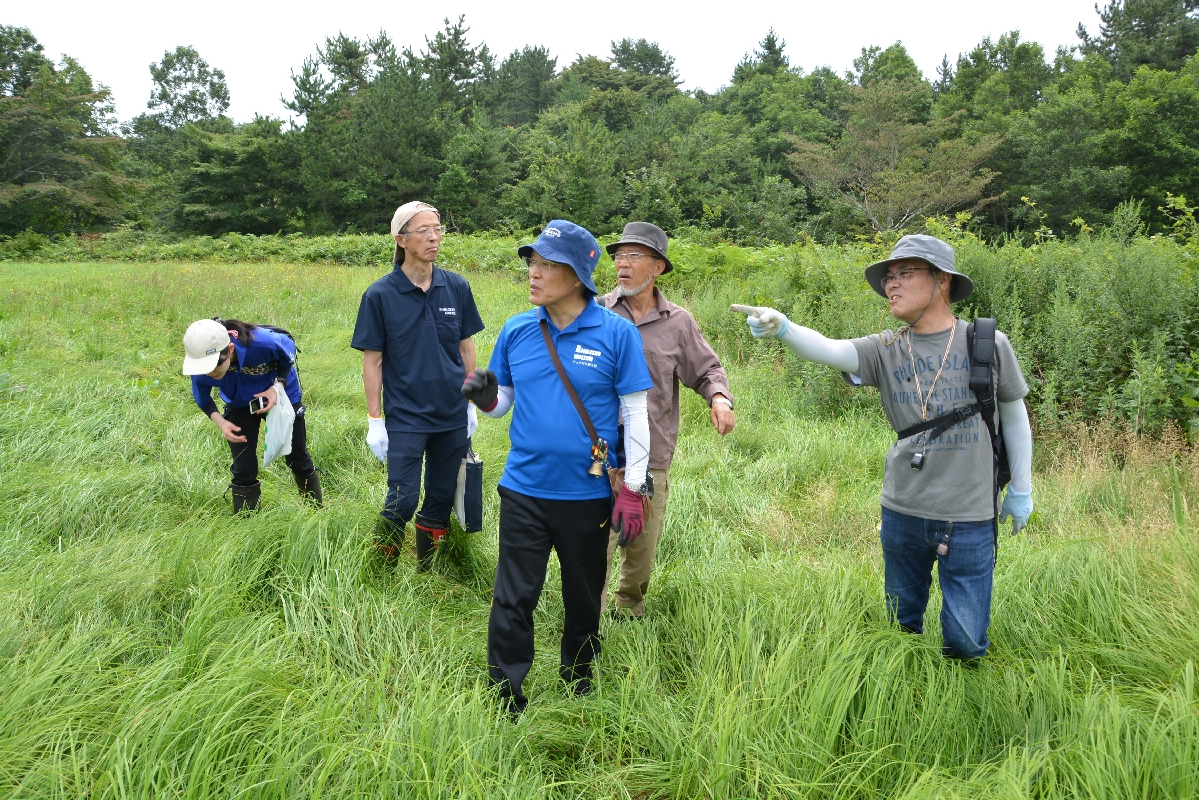 ぼんてん山の登山道入り口付近で植物を観察する参加者