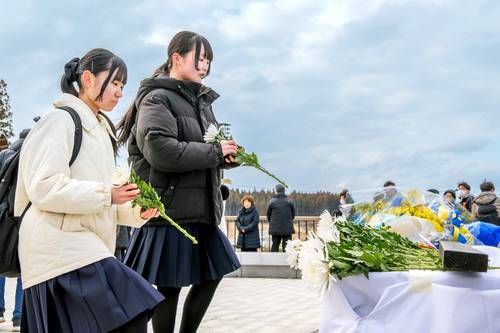 犠牲者の冥福を祈り、献花台に花を手向ける参列者=11日、野田村(大粒来仁撮影)