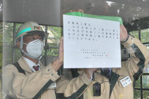 建物を解体することを知らせる張り紙を貼る関係者=8日、十和田市