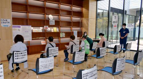 接種後に約15分間の健康観察をする高齢者ら。集団接種初日は約300人が来場した=14日、八戸市総合保健センター