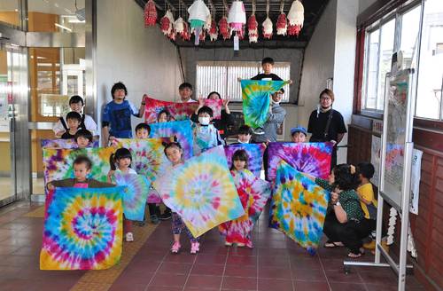 「タイダイ染め」で作ったほっかむりを広げて見せる子ども=6日、八戸市のJR陸奥湊駅
