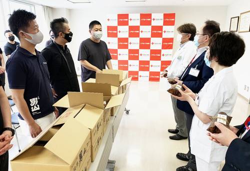 八戸赤十字病院のスタッフにおにぎりを寄贈する成澤由浩さん(左から3人目)と浜田寿人さん(同2人目)