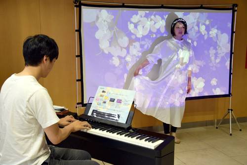 三沢駅前交流プラザ「みーくる」に設置されたストリートピアノとミュージックタペストリー。白い服でスクリーンの前に立つと花が投影される
