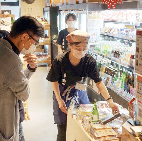 来店客に八戸圏域の物産を紹介する八戸学院大の学生(手前右)=3日、東京・内幸町