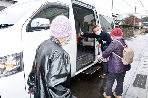 法人職員に迎えられ、車両に乗り込む桜ケ丘4丁目の住民=11月24日、八戸市