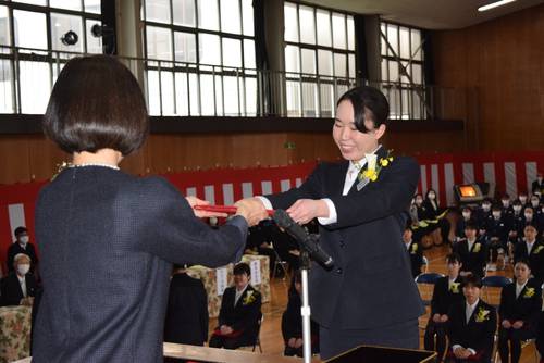 岡本潤子校長(左)から卒業証書を受け取る卒業生