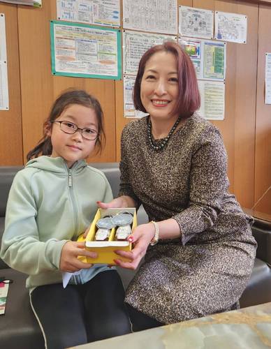 星崎弓奈さん(左)にチェリージュビリーを手渡す長塚京子代表=2月27日、沖縄県うるま市立南原小(長塚青果提供)