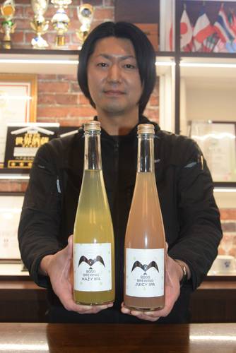 青森県産ホップを使ったクラフト酒「8000BREWING」をPRする駒井伸介常務。左から「HAZY IPA」「JUICY IPA」=12日、八戸市の八戸酒造