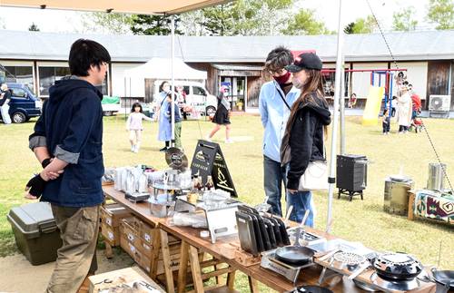 キャンプグッズの展示販売で品定めをする来場者