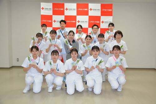 客室乗務員の成田安里さん(中列左から3人目)からスズランの切り花を受け取った八戸赤十字病院の看護師