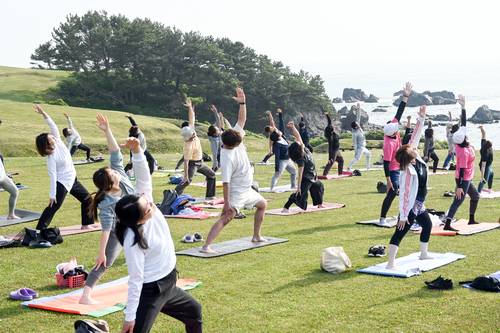 種差天然芝生地で始まった「種差朝ヨガ」。多くの人が参加し、楽しんだ=27日、八戸市鮫町