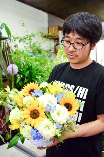 青森県産のヒマワリなどを使ったフラワーアレンジメントを紹介する中村大祐専務=20日、八戸市の「お花の陽光園」