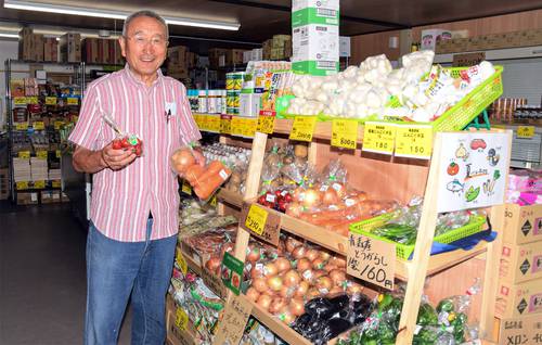 規格外の野菜を手に、店舗をPRする柏崎進一代表=4日、おいらせ町